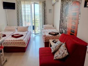 a living room with two beds and a red couch at Studio La Casa in Soko Banja