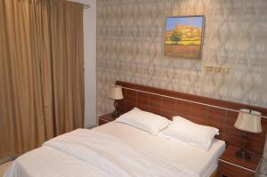 a bedroom with a bed with white sheets and pillows at Holiday Season in Tabuk