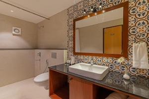 a bathroom with a sink and a mirror and a toilet at Sterling Karwar in Kārwār