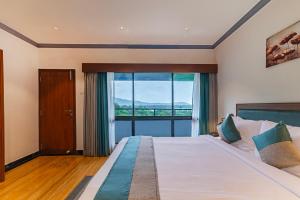 a bedroom with a large bed with a large window at Sterling Karwar in Kārwār