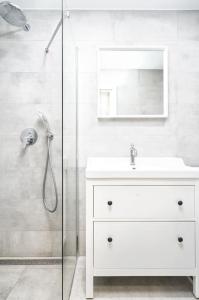 a white bathroom with a sink and a shower at Apartment in Trakai by the lake! in Trakai