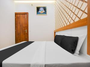 a bedroom with a white bed and a wooden door at Hotel O Green In in Bathinda +22 photos