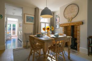 a dining room with a table and a fireplace at Victory Cottage in Lymington