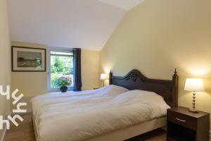 a bedroom with a large white bed and a window at OV592- 2P apartment in the heart of Giethoorn in Giethoorn +21 photos