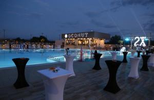 a large pool with white tables in front of a building at Casino Motel Senator in Gevgelija