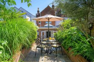 a table and chairs with an umbrella in a garden at Victory Cottage in Lymington