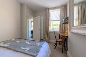 a bedroom with a bed and a desk and a window at Victory Cottage in Lymington