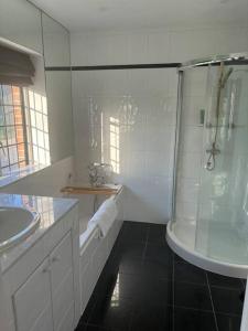 a white bathroom with a shower and a sink at Picturebook cottage on prestigious polo estate in Stedham +82 photos