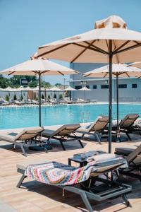 a group of lounge chairs and umbrellas next to a pool at Casino Motel Senator in Gevgelija
