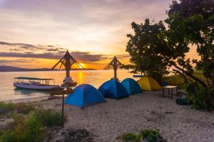 a group of tents on a beach with a boat at Boat Trip in Riung
