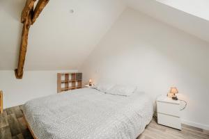 1 dormitorio blanco con 1 cama y suelo de madera en Dépendance au charme local, en Saint-Carné