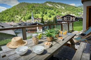 a table with bowls and plates of food on a balcony at Le Petit Capricia - OVO Network in La Clusaz