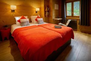 a bedroom with a large bed with an orange blanket at Le Petit Capricia - OVO Network in La Clusaz +10 photos