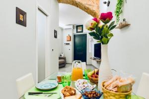 a table with a vase of flowers and food on it at Sun Apartments in Agrigento