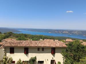 a house on a hill with a river in the background at Portes du Verdon in Aiguines