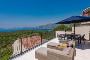 balcone con tavolo, sedie e ombrellone di Villa Dundo Marijo a Kručica