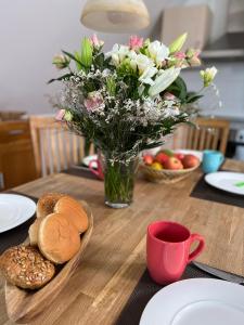 una mesa de madera con un jarrón de flores y pan en FeWo Kapitäns-Seeblick, en Göhren-Lebbin