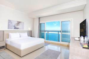 马特鲁港Triumph White Sands Hotel的卧室里有一张白色的床和一扇大窗户