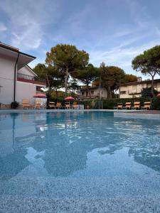 a large swimming pool with tables and chairs at Casa Bianca Village Apartments in Lignano Sabbiadoro