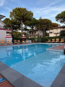 a large blue swimming pool with chairs and umbrellas at Casa Bianca Village Apartments in Lignano Sabbiadoro