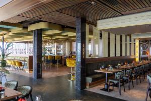 a restaurant with wooden ceilings and tables and chairs at Strandhotel Het Hoge Duin in Wijk aan Zee
