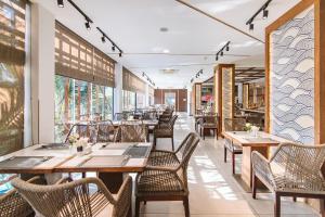a restaurant with wooden tables and chairs and windows at Le Palmier Ho Tram Resort - Beachfront with Private Beach in Ho Tram