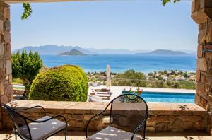 a patio with chairs and a view of the ocean at White Stone Villa in Marathonas +59 photos