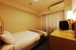 um quarto de hotel com uma cama e uma secretária com uma televisão em Chisun Inn Kamata em Tóquio