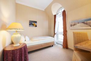 a small bedroom with a bed and a window at Strandhotel Sylt Westerland in Westerland