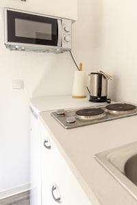 a kitchen with a stove and a microwave at Bluegate Suite - Airport Guesthouse in Kelsterbach