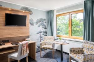 a hotel room with a tv and chairs and a table at Romantik Hotel Waldschlösschen in Schleswig