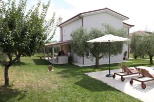 a white house with two benches and an umbrella at Villa Torri Appartments in Torano Nuovo