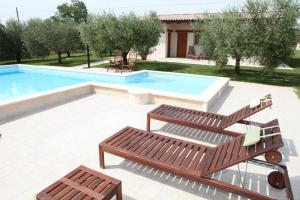 a patio with two benches and a swimming pool at Villa Torri Appartments in Torano Nuovo
