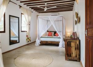 a bedroom with a bed with a mosquito net at Bahati Sunset Bungalows Michamvi in Michamvi