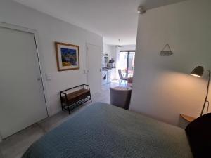 a bedroom with a bed and a living room at FLEUR DE SEL logement de 21m2 avec prêt vélos, cuisine et sdb privées avec terrasse clôturée de 17m2 in Batz-sur-Mer