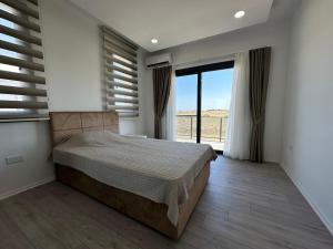 a bedroom with a bed and a large window at ISKELE BAHCELER de KIRALIK TRIPLEX HAVUZLU LUKS VILLA in İskele +9 photos