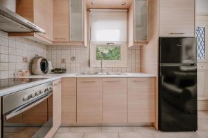 a kitchen with wooden cabinets and a black refrigerator at K&F Apt in the center of Ierapetra by Hospi in Ierápetra +11 photos