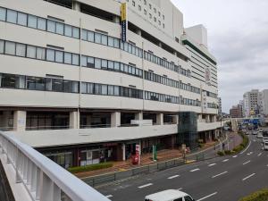 a tall white building on the side of a street at Smile Hotel Tokushima in Tokushima