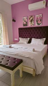a bedroom with a large bed with purple walls at Trattorias Holiday Home in Varkala