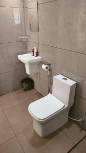 a bathroom with a white toilet and a sink at Trattorias Holiday Home in Varkala