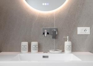 a bathroom sink with three bottles of soap and a light at Fully Furnished Pink Apartment 2 in Treviso