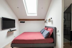 a bedroom with a red bed with a tv at Grange Caliana in La Vineuse