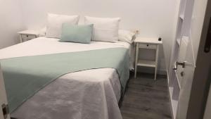 a bed with a green and white blanket and pillows at Luz de Mar in O Grove