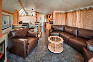 a living room with a leather couch and a table at Ferienhaus Chilllout Chalets Daun-Kradenbach in Kradenbach