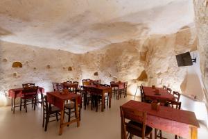 a restaurant in a cave with wooden tables and chairs at Il Belvedere in Matera