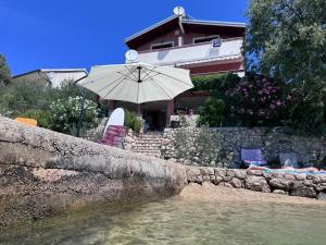 a house with an umbrella next to a body of water at Misho Apartments in Kruševo +25 photos