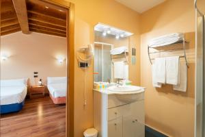 łazienka z umywalką, lustrem i łóżkiem w obiekcie Hotel Alda Lalín w mieście Lalín