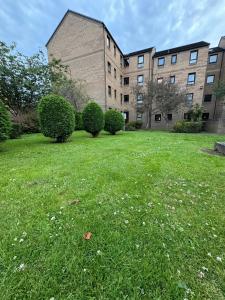 a grassy yard with bushes in front of a building at Two bedroom flat close to meadows with free parking by parking permit in Edinburgh
