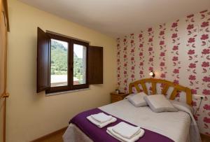 a bedroom with a bed with two towels on it at Hotel Rural Somiedo in Valle de Lago