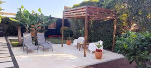 a patio with chairs and a wooden pergola at 2Azores With Comfort and Style in Ponta Delgada